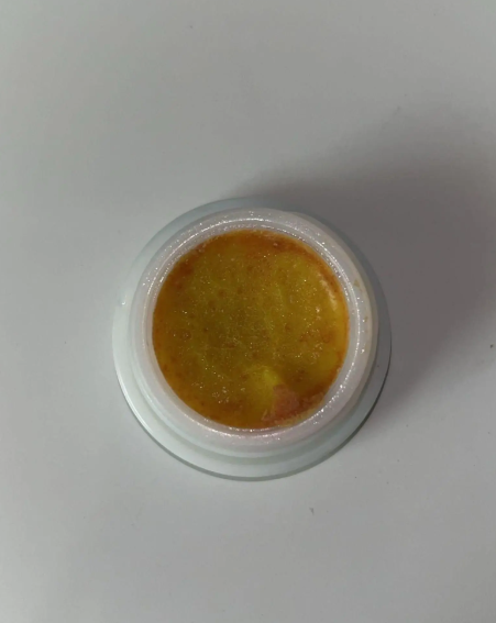 Small container of brown powder on a white background