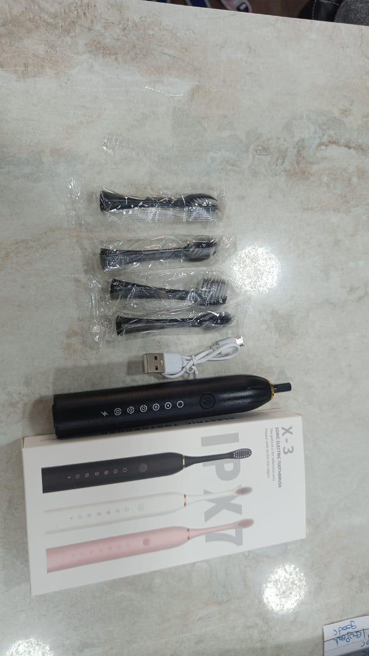 Electric toothbrush set with multiple heads and packaging on a light surface