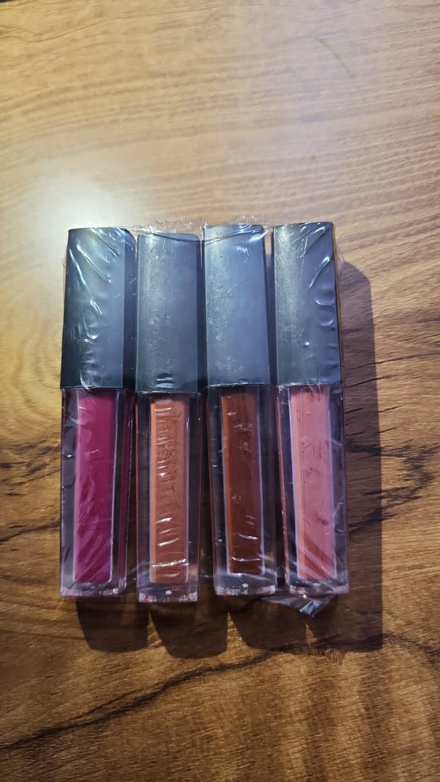 Four lip gloss tubes in different colors on a wooden surface