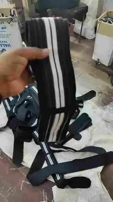 Black and white striped belt held by a hand in an indoor setting with boxes and furniture.