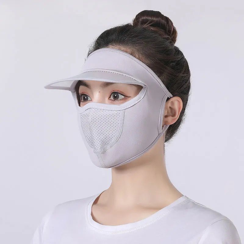 Person wearing a white face mask and visor on a light gray background