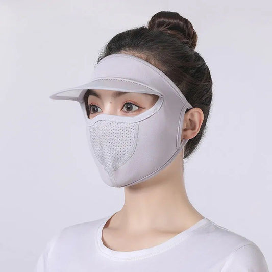 Person wearing a white face mask and visor on a light gray background