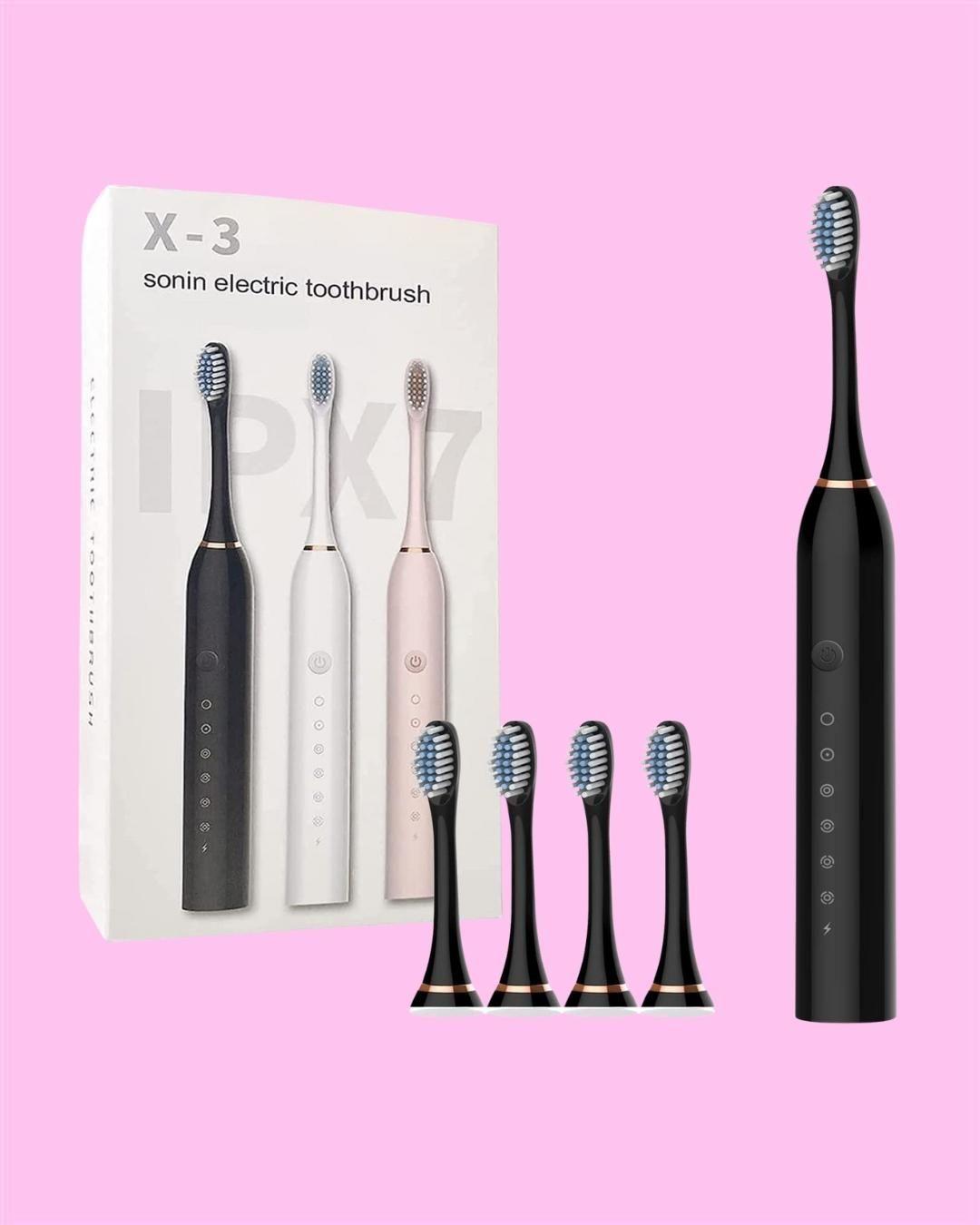 Black electric toothbrush with packaging and additional brush heads on a pink background