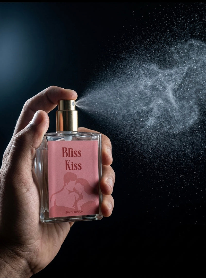 Hand holding a perfume bottle labeled 'Bliss Kiss' with spray action against a dark background