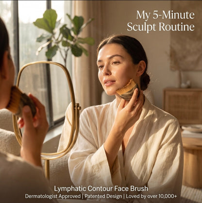 Woman in a robe applying a product to her face with a brush, in a home setting.