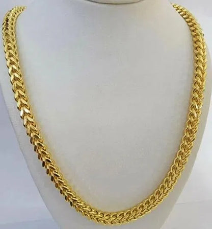 Gold chain necklace on a mannequin bust with a plain background