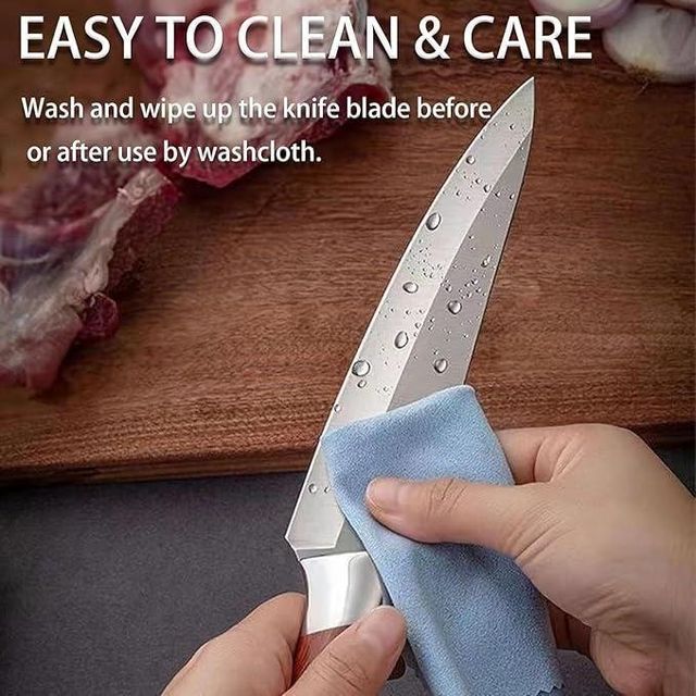 Person cleaning a knife blade with a cloth on a wooden cutting board.