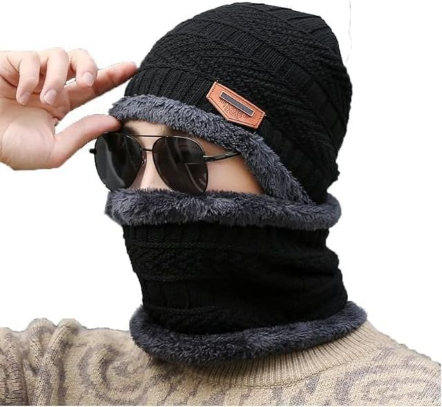 Black knit beanie with gray fur trim worn by a person, with sunglasses on top of the head.