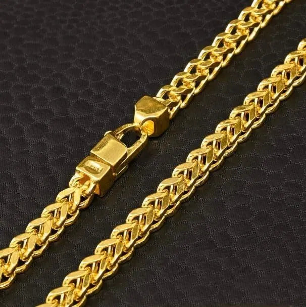 Gold chain necklace with a clasp on a black textured background