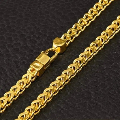 Gold chain necklace with a clasp on a black textured background