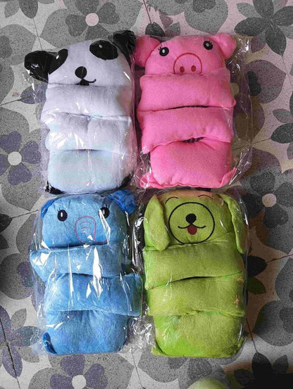 Four animal-themed baby booties in plastic packaging on a patterned surface.