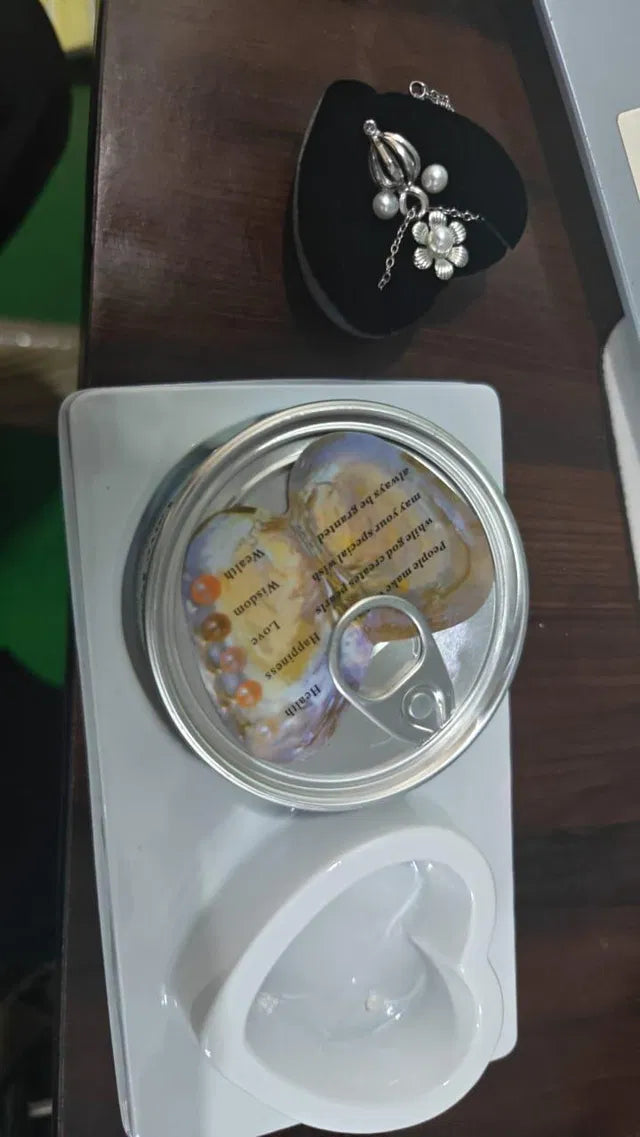 Heart-shaped container with a lid, containing small objects and text, on a wooden surface.